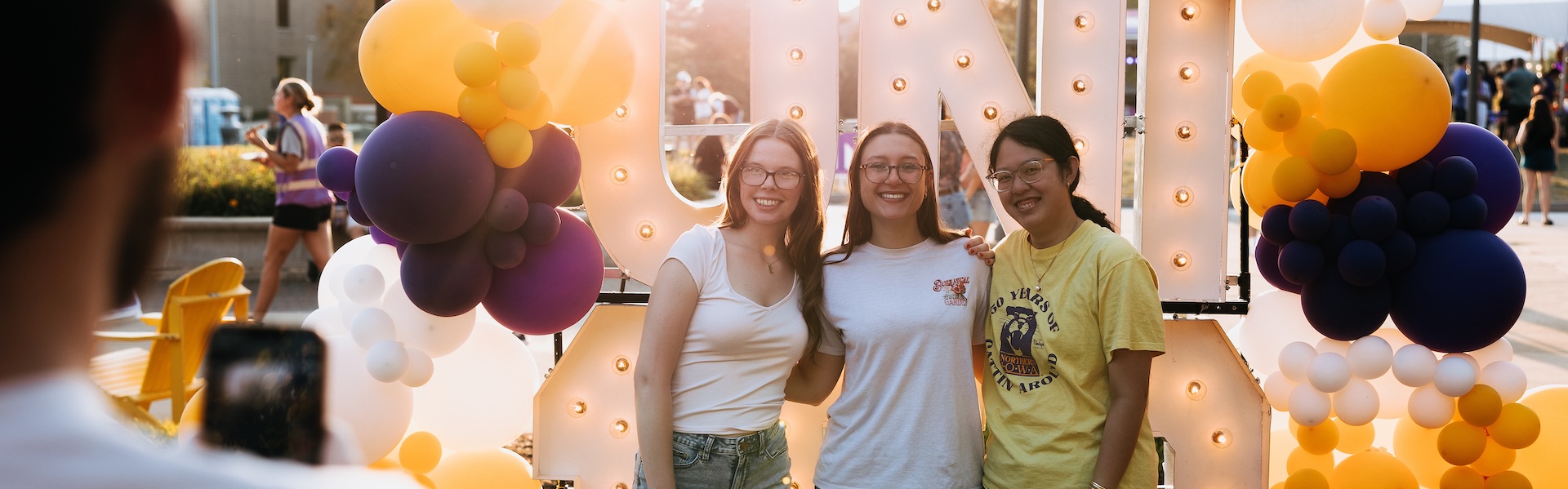 UNI students taking a picture in front of the big UNI 150 pop-up.